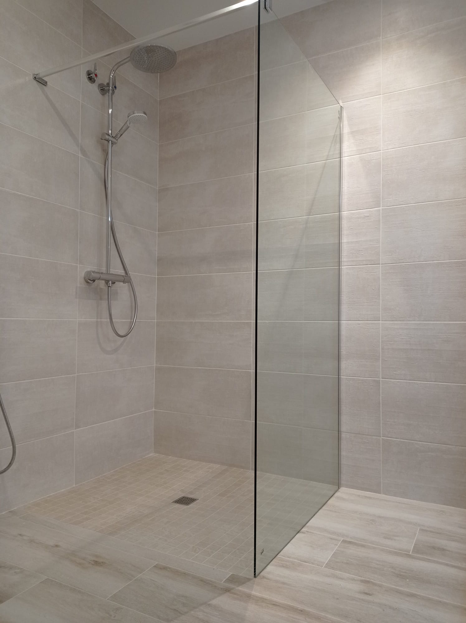 Plato de ducha de obra con alicatado cerámico y mampara de vidrio en el Maresme