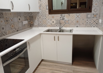 Cocina con alicatado decorativo y encimera en esquina en el Maresme