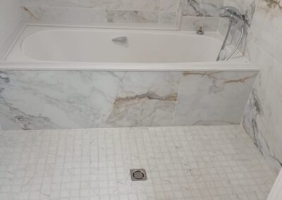 Baño con alicatado efecto mármol y plato de ducha de obra en el Maresme