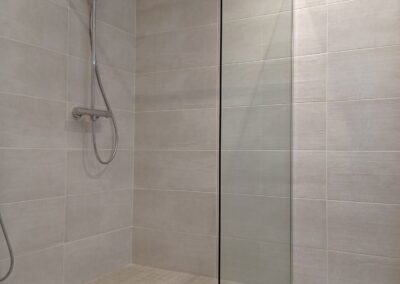 Ducha de obra con plato integrado y mampara de vidrio en baño reformado en el Maresme