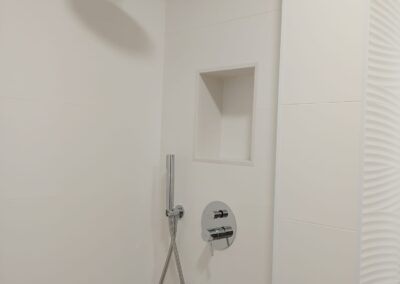 Ducha empotrada con rociador superior y nicho en pared en baño reformado en el Maresme
